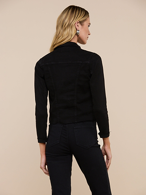 A woman with long blonde hair is shown from the back wearing the Janelle Jean Jacket and black pants, standing against a plain beige background.