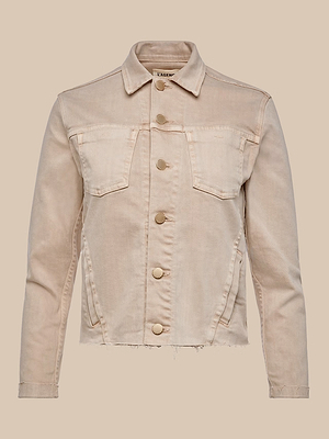 The Janelle Jean Jacket in light beige stretch denim features metal buttons, two chest flap pockets, side pockets, and a raw frayed hem, shown on a plain beige background.