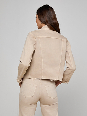 A woman with long brown hair is seen from the back, wearing the Janelle Jean Jacket in light oatmeal beige and matching high-waisted stretch jeans, set against a plain light gray background.