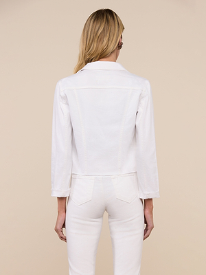 A person with long blonde hair is seen from the back wearing the Janelle Jean Jacket, a feminine-fit white denim piece, along with matching white stretch denim pants against a plain beige background.