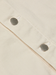 Close-up of two silver snap buttons on light beige fabric, likely from the Janelle Jean Jacket, with visible stitching and textured detail.