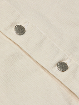 Close-up of the cream-colored stretch denim Janelle Jean Jacket, featuring two metallic snap buttons and detailed stitching that highlights its textured fabric.