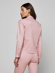 A woman with long brown hair wears the slim fit Janelle Coated Jean Jacket in light pink with matching pants, standing against a plain off-white background and looking to her left.