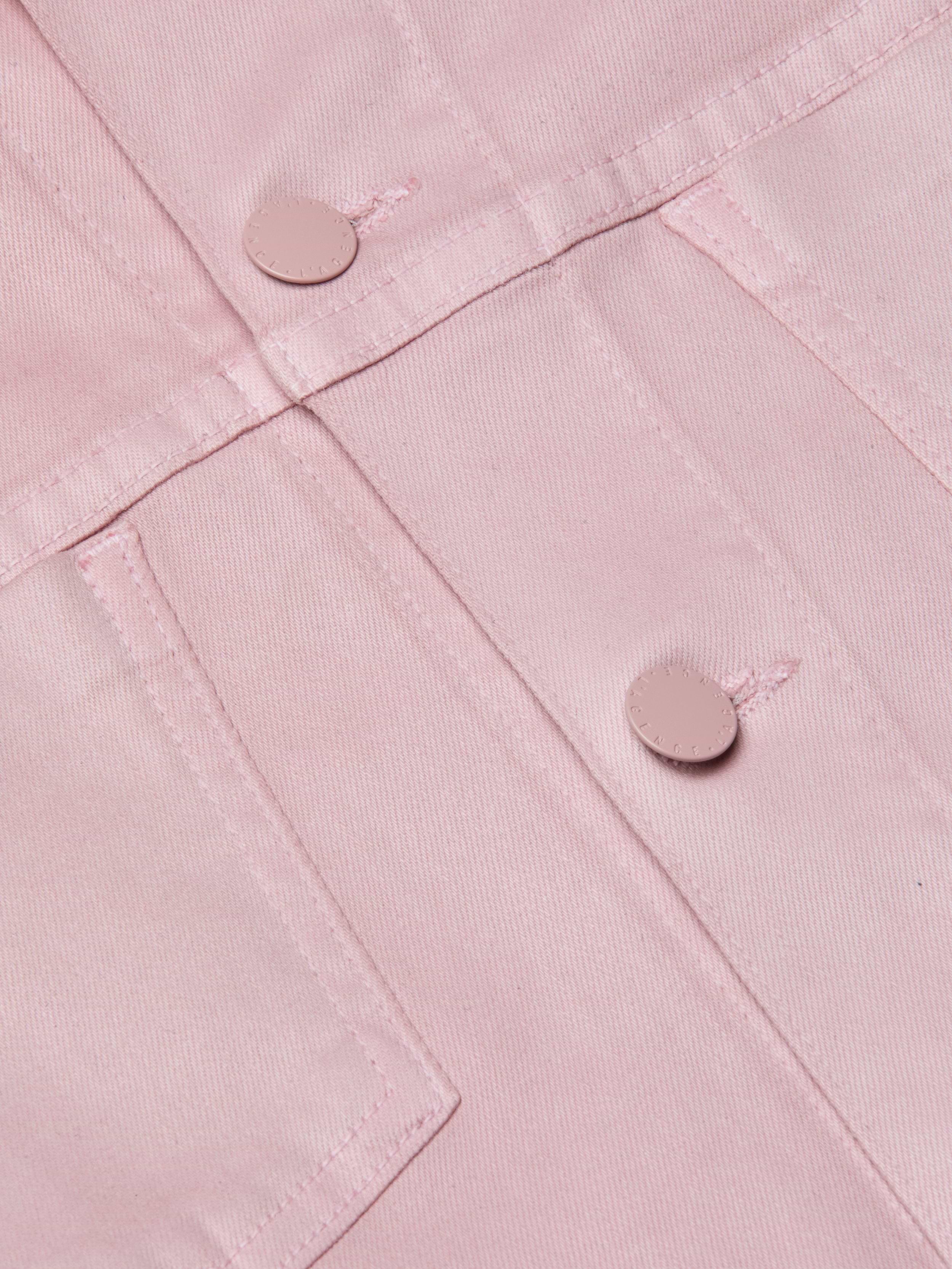 Close-up of the Janelle Coated Jean Jacket in light pink, featuring metal buttons and intersecting stitched seams that highlight the fabric’s textured structure.