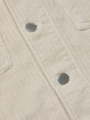 Close-up of the L'AGENCE Janelle Corduroy Jacket in beige, featuring vertical ridges, two silver snap buttons, and part of a chest pocket.