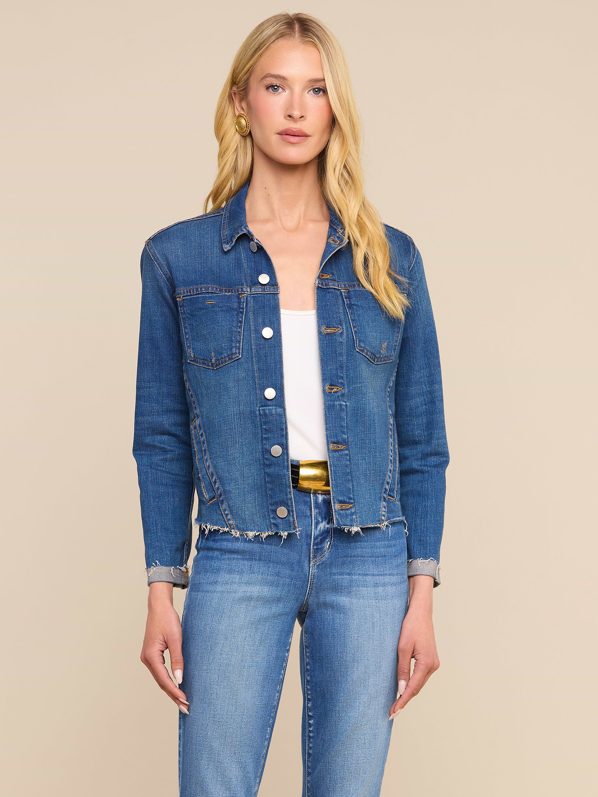 A woman with long blonde hair wears the Janelle Jean Jacket made from stretch denim, along with matching jeans, standing against a plain light background.