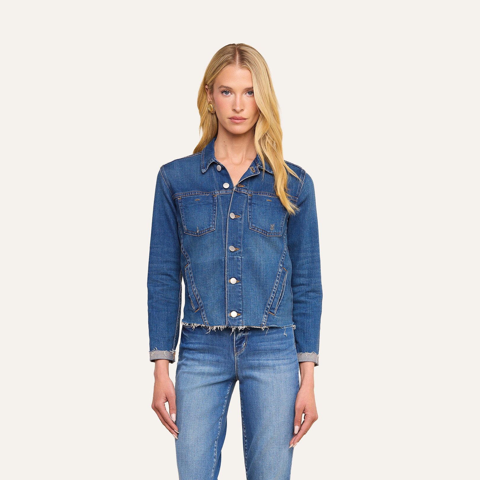 A woman with long blonde hair wears the Janelle Jean Jacket and stretch denim jeans, standing against a plain, light background and facing forward with a neutral expression.