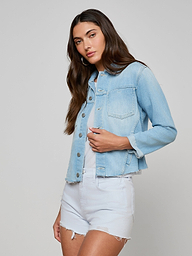 Wearing the Janelle Jean Jacket over a white shirt and light denim shorts, a woman with long brown hair stands against a plain off-white background.