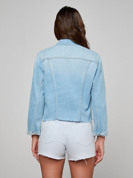 A woman with long brown hair, seen from behind, wears the Janelle Jean Jacket and white frayed hem shorts against a plain, light background.