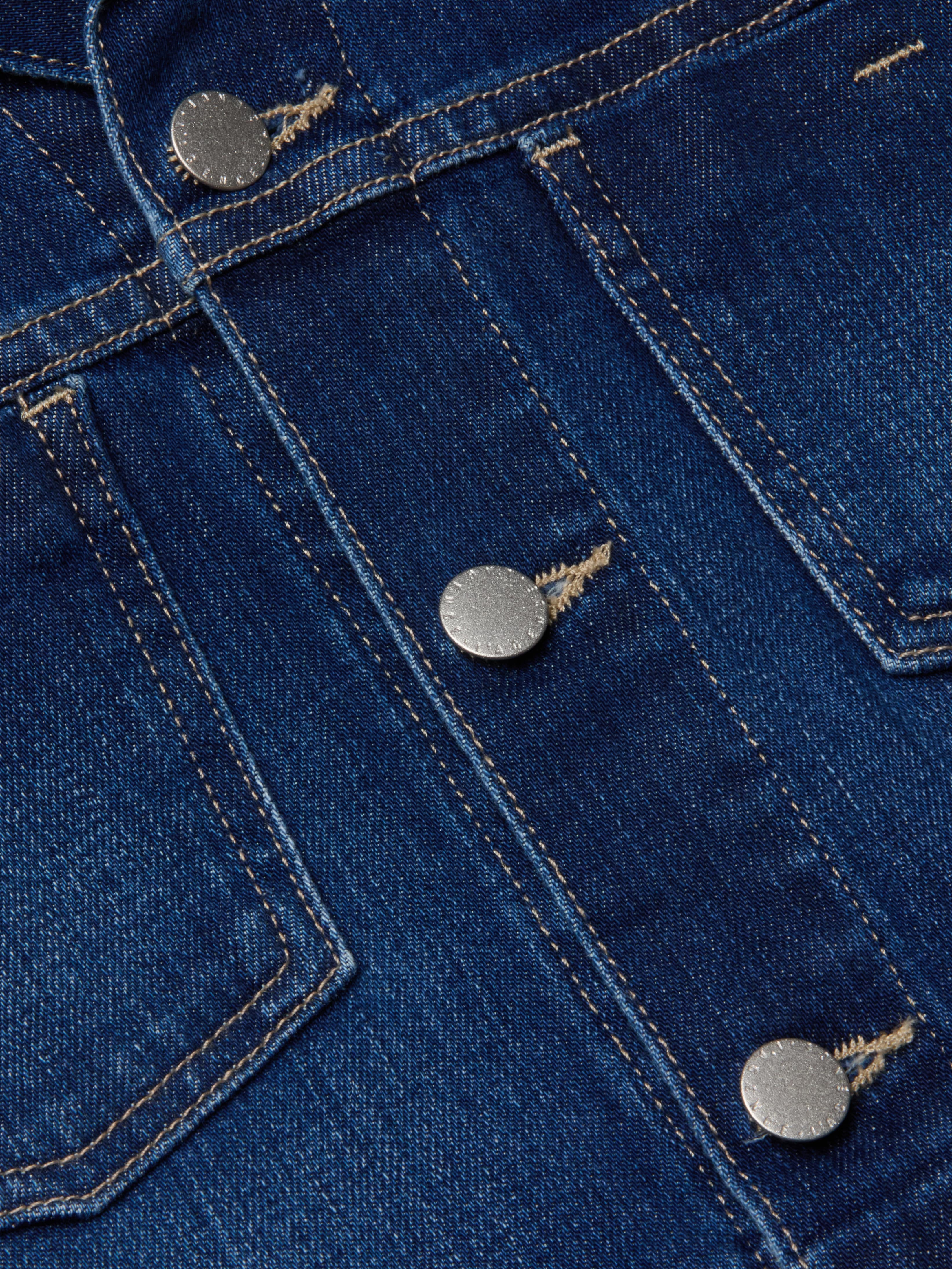 Close-up of blue denim fabric with visible stitching and silver metal buttons, featured on the Janelle Jean Jacket.