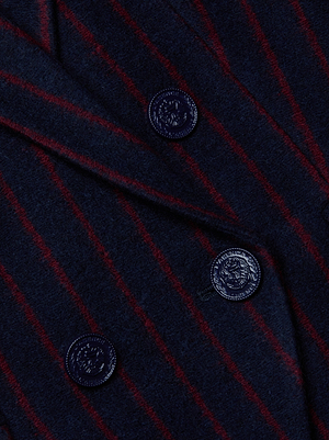 Close-up of the L'AGENCE Kenzie Pinstriped Blazer, a dark navy wool-blend piece with red diagonal pinstripes and three black crest-embossed buttons, showcasing its sophisticated double-breasted design.