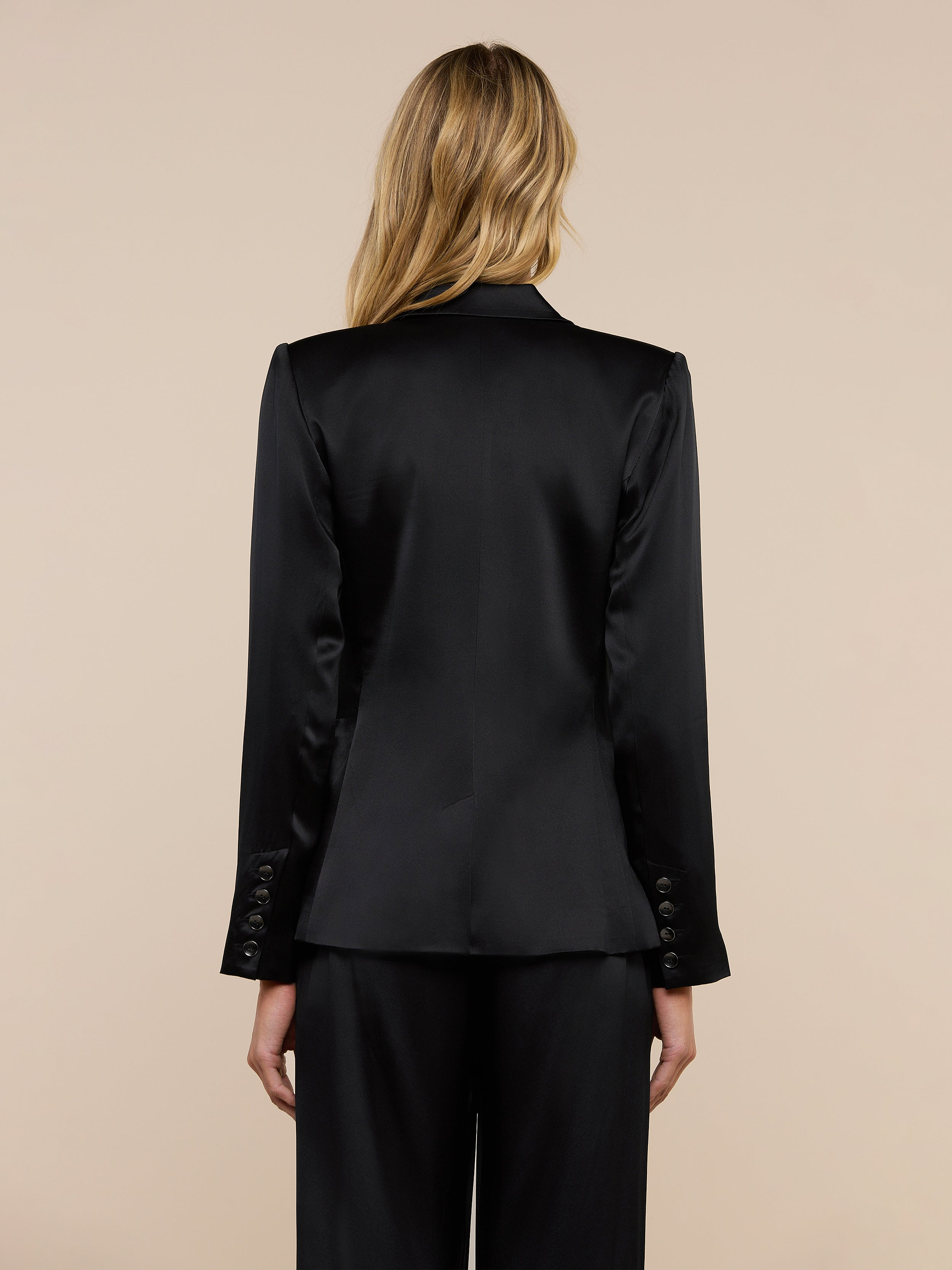 A woman with blonde hair is shown from the back wearing the Colin Silk Charmeuse Blazer and matching pants against a plain light background.
