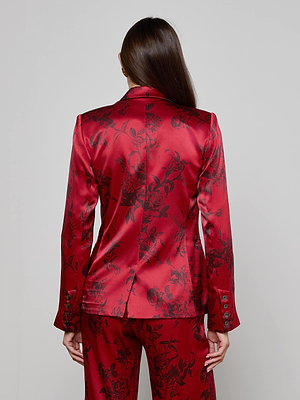 A person with long straight brown hair seen from behind wears the L'AGENCE Colin Silk Blazer, a shiny red floral print suit featuring buttoned sleeves and a tailored fit.