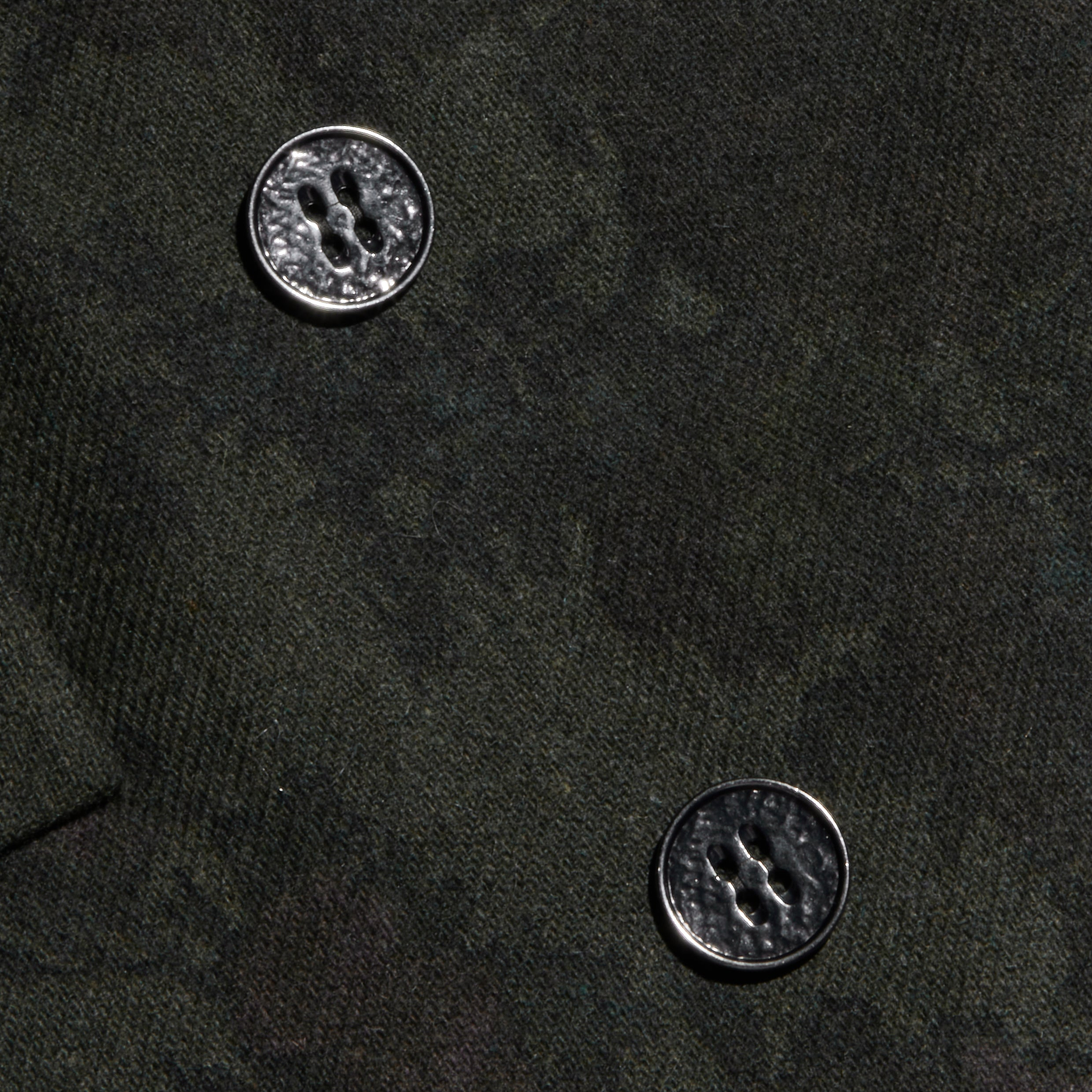 Close-up of the Jayda Blazer’s dark Italian wool blend fabric with two four-hole metallic buttons. The rich texture of the fabric and the glossy finish of the buttons are clearly highlighted.