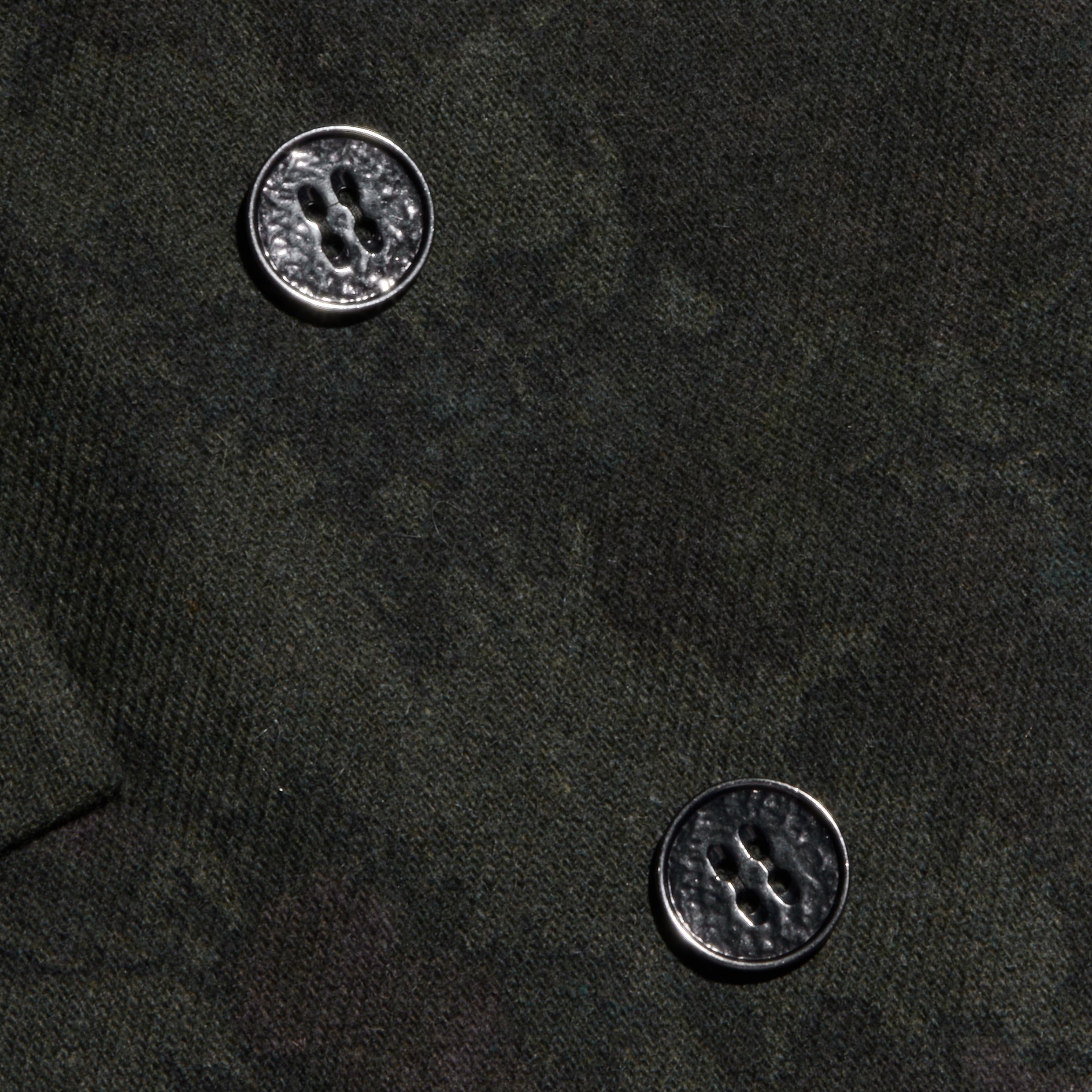 Close-up of the Jayda Blazer’s dark Italian wool blend fabric with two four-hole metallic buttons. The rich texture of the fabric and the glossy finish of the buttons are clearly highlighted.