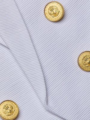 Close-up of the Brooke Blazer in ribbed ottoman fabric, showcasing three shiny gold embossed buttons in a classic double-breasted design.