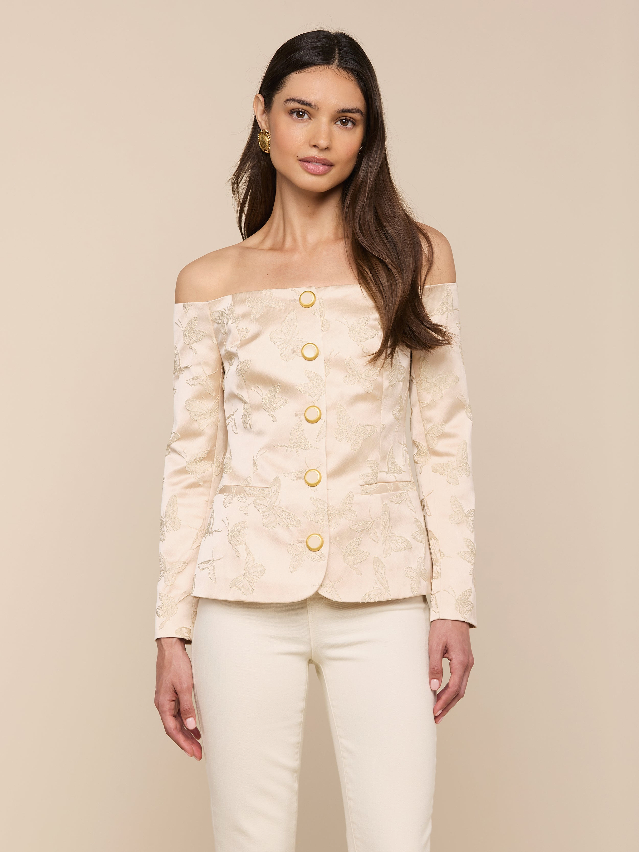A woman wearing the Alice Blazer Top in cream-colored jacquard satin with gold buttons, paired with matching cream tailored suiting pants, stands against a plain light background.