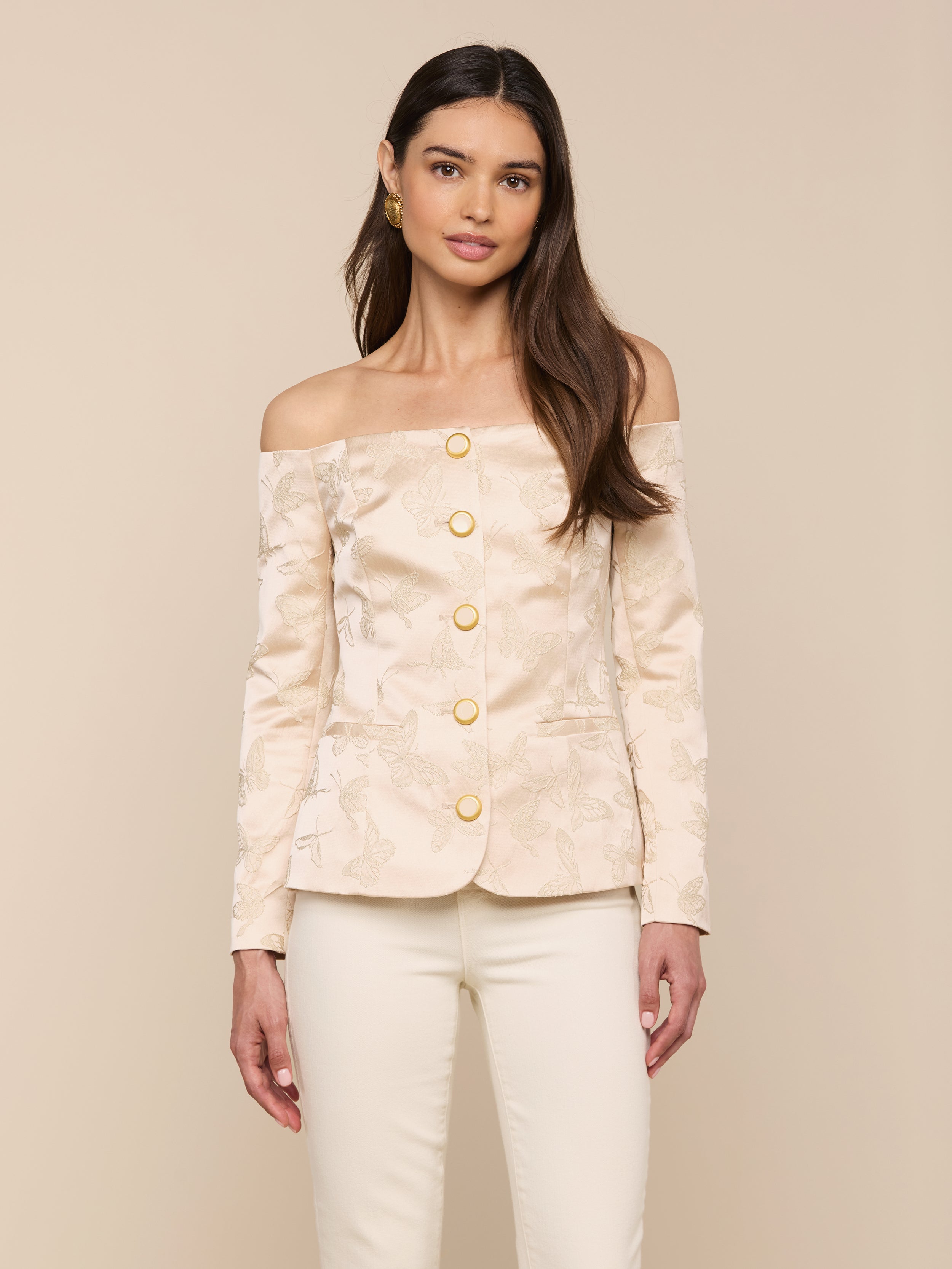 A woman wearing the Alice Blazer Top in cream-colored jacquard satin with gold buttons, paired with matching cream tailored suiting pants, stands against a plain light background.