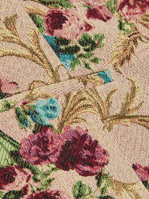 Close-up of the Alice Blazer Top's floral tapestry fabric, featuring red, blue, and pink flowers with green leaves on a light beige background. Two overlapping edges form an angular shape at the center.