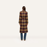 A person stands with their back to the camera, wearing the Kolina Tweed Long Coat—an elegant plaid design featuring a waist-cinching belt—paired with blue jeans against a plain, light background.