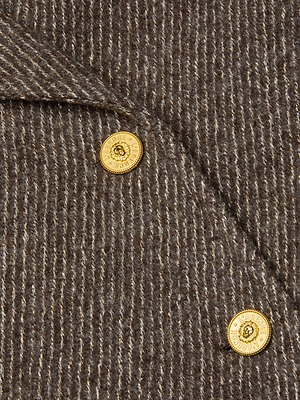 Close-up of the Kolina Long Coat's textured brown and beige striped wool-blend fabric, featuring two gold buttons with engraved text and decorative details.
