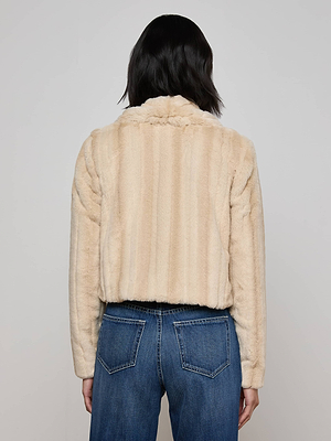 A person with shoulder-length dark hair is seen from the back wearing the L'AGENCE Davy Faux Fur Jacket in light beige stripes and blue jeans with visible back pockets, set against a plain light background.
