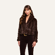 A woman with long brown hair, wearing gold earrings and the Davy Faux Fur Jacket paired with matching brown pants, stands against a plain light background and looks at the camera with a neutral expression.