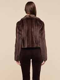 A person with straight brown hair is shown from the back, wearing the retro-inspired Davy Faux Fur Jacket and dark brown pants against a plain light background.