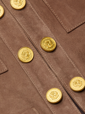 Close-up of the Jayde Collarless Jacket in brown suede, showcasing decorative gold embossed buttons arranged in two rows near stitched pocket flaps—a stylish layering piece for any wardrobe.