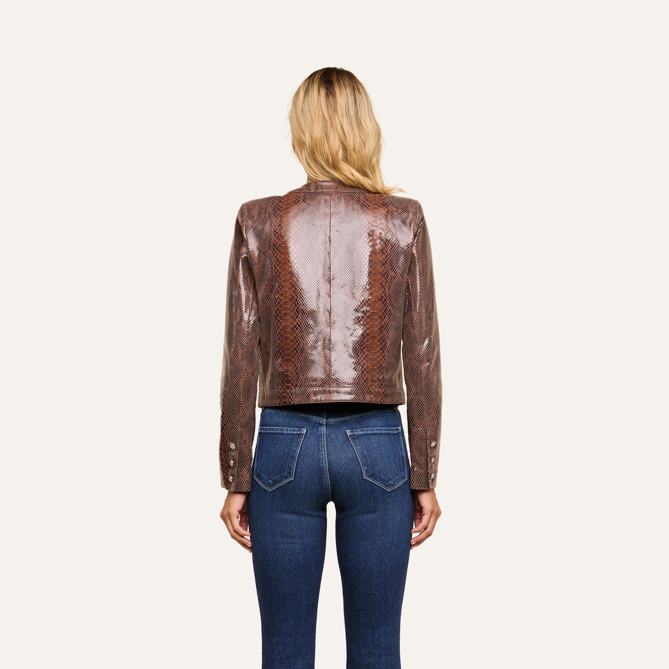 A woman with long blonde hair, seen from behind, wears the Jayde Coated Suede Jacket and blue jeans, standing against a plain white background.