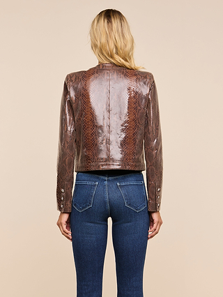 A woman with blonde hair, seen from behind, wears the Jayde Leather Jacket—a high-shine brown snake print design—paired with blue jeans, standing against a plain beige background.