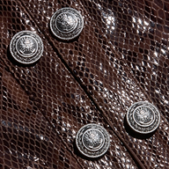 Close-up of the Jayde Coated Suede Jacket in a shiny, dark brown snake print, detailed with four silver buttons featuring crown and crest emblems.