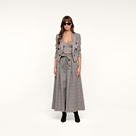 A woman wearing sunglasses, the Lila Tweed Blazer with a matching crop top and wide-leg pants, and black boots stands against a plain white background.