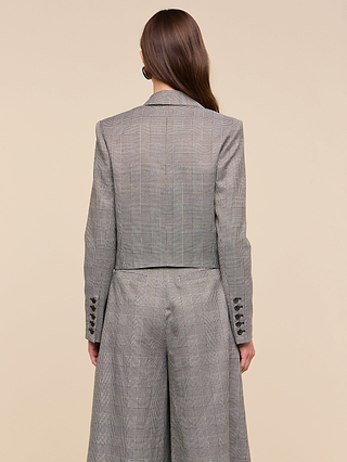 A woman with long brown hair wears the Lila Tweed Blazer and matching wide-leg trousers, standing with her back to the camera against a beige background.