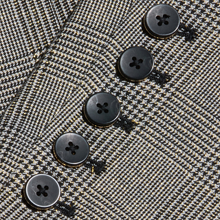 Close-up of five black buttons sewn onto the gray plaid houndstooth fabric of the Lila Tweed Blazer, likely showing the sleeve detail.