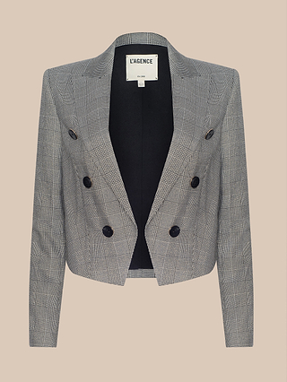 The Lila Tweed Blazer is a gray plaid, double-breasted cropped blazer with black buttons, long sleeves, and an open front, displayed on a beige background.