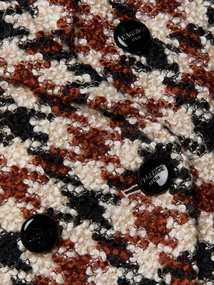 A close-up of the Marie Houndstooth Tweed Blazer shows textured black, brown, and white fabric with three glossy black PARIS-engraved buttons on this stylish oversized piece.