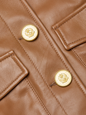 Close-up of the Kumi Cropped Leather Jacket by L'AGENCE, crafted from Italian lambskin leather with two gold crest-embossed buttons and two flap pockets.