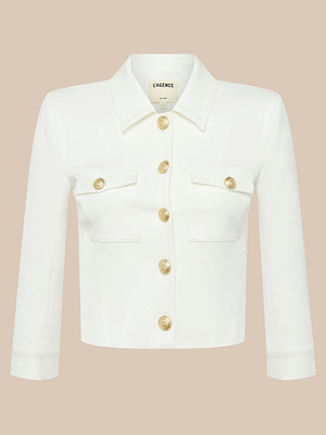 La chaqueta corta Kumi es una prenda blanca de manga tres cuartos con cuello y dos bolsillos en el pecho, adornada con botones redondos en relieve dorados y confeccionada en tejido elástico de traje, tal y como se muestra sobre un fondo beige neutro.