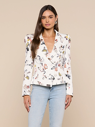 A woman with long brown hair wearing the Bethany Structured Blazer—a figure-flattering butterfly print piece—paired with light blue jeans, stands against a plain light background.