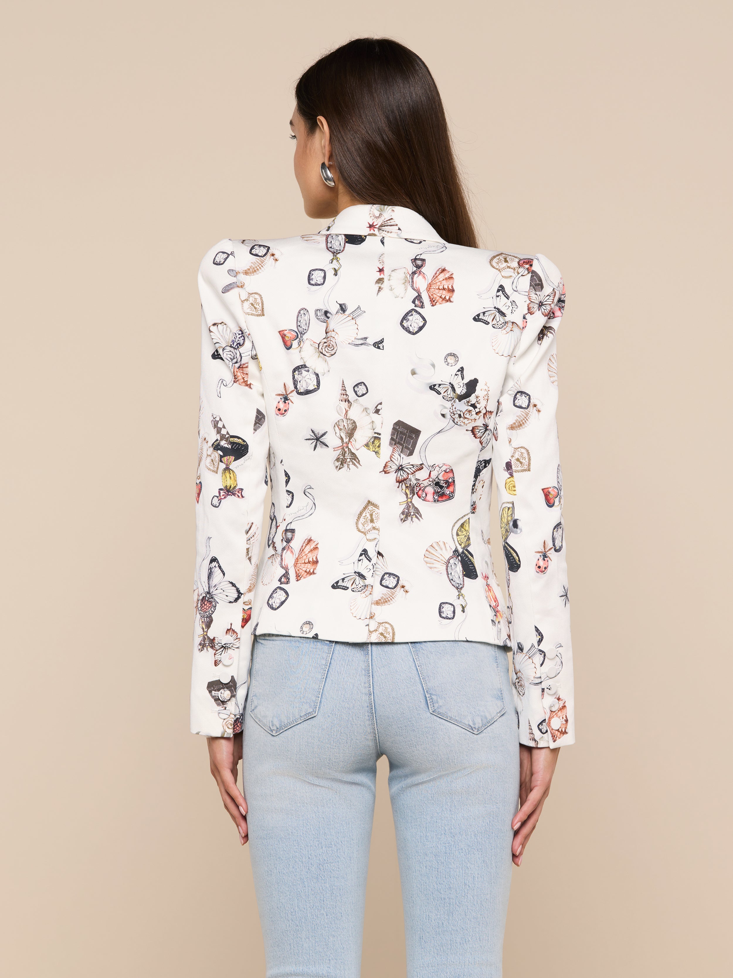 A woman with long brown hair is shown from the back against a plain background, wearing the Bethany Structured Blazer with a butterfly print and light blue jeans.