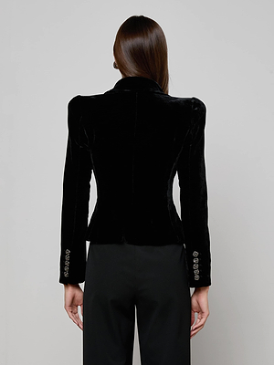 A person with straight brown hair is seen from behind wearing the L'AGENCE Bethany Velvet Blazer, featuring crystal-embellished sleeve buttons, and black pants, standing against a plain light gray background.