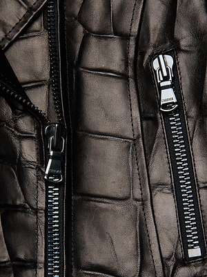 Close-up of the Lyric Leather Peplum Jacket by L'AGENCE, featuring croc-embossed black lambskin leather, two visible silver zippers, and detailed stitching that highlights its luxe texture.