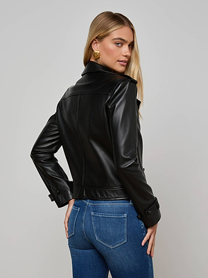 Woman with long blonde hair wears the Xoey Cropped Leather Trench Coat and blue jeans, standing with her back turned and looking over her shoulder against a plain light background.