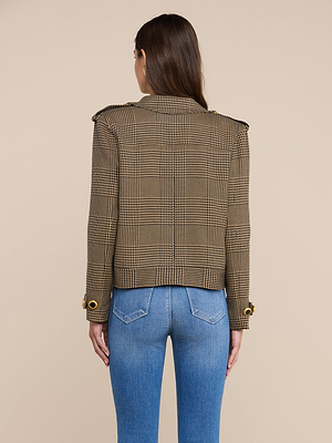 A woman is seen from the back, wearing the Xoey Cropped Trench Coat—a brown plaid blazer with buttoned cuffs—paired with light blue jeans, standing against a plain beige backdrop.