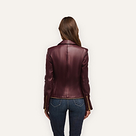 A person seen from behind wearing an Ottilie Leather Blazer in burgundy with gold sleeve zippers and blue jeans, the outfit creating a sharp power dressing look with an hourglass silhouette.