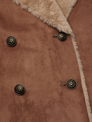 Close-up of the Citron Faux Fur Maxi Coat by L'AGENCE, featuring brown vegan suede, a beige faux shearling collar, and four decorative dark metal buttons with an engraved design.
