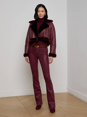 A woman stands in a corner of a room wearing the Pike Shearling Leather Jacket, styled with a turtleneck, flared pants, and matching heels for a chic winter look combining cozy layers and sleek textures.