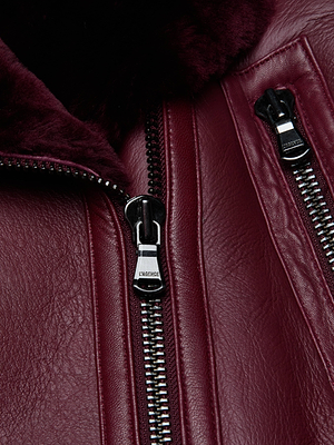 Close-up of the Pike Shearling Leather Jacket in burgundy, featuring silver zippers and soft dark burgundy lamb shearling lining. The partially open main zipper reveals its plush interior—ideal for staying warm in winter.