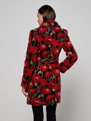 A woman stands with her back to the camera, wearing the L'AGENCE Tristan Sherpa Midi Coat in red poppy print with a belt and black pants, set against a plain light gray background.